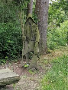 a statue of a man with a beard sitting next to a tree at Zur Waldhufe in Königswalde