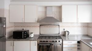 a kitchen with white cabinets and a stove and a microwave at 2 bdr apt in Palmarejo Baixo, near seafront - LCGR in Praia