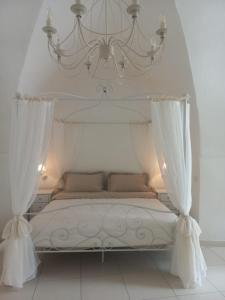 1 dormitorio con cama blanca y lámpara de araña en Le Stanze del Castello, en Ascoli Satriano