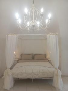 1 cama blanca con lámpara de araña en una habitación en Le Stanze del Castello, en Ascoli Satriano