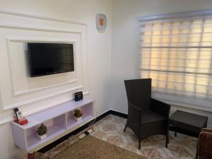 uma sala de estar com televisão e duas cadeiras em Adel’s Place em Abuja