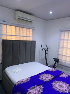 a bedroom with a bed and a chair and windows at Adel’s Place in Abuja