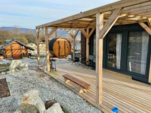 a wooden deck with a large barrel on it at Tiny House with Mountain Views in Turany