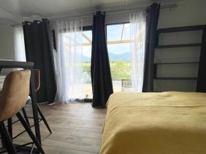 a bedroom with a bed and a large window at Tiny House with Mountain Views in Turany