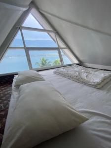 białe łóżko w pokoju z oknem w obiekcie Vandu's View Guest house & Restaurant w mieście Tuktuk