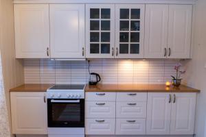 a kitchen with white cabinets and a stove at Senja, 2 BR apartment, surrounded by the northern lights and the midnight sun in Finnsnes