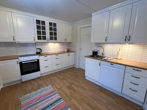 a kitchen with white cabinets and white appliances at Senja, 2 BR apartment, surrounded by the northern lights and the midnight sun in Finnsnes