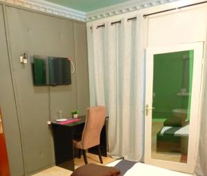 ein Zimmer mit Schreibtisch und Stuhl und ein Schlafzimmer in der Unterkunft L'Address in Cotonou