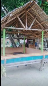 Bacungan的住宿－A&Z Nagtabon Lodge，一个带木屋顶和长凳的游泳池