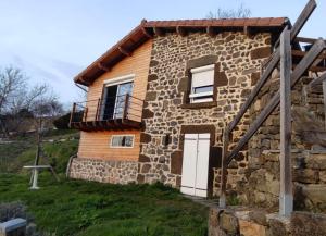 een stenen huis met een veranda en een balkon bij Maison vigneronne climatisée in Polignac