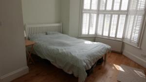 a bedroom with a bed and a table and two windows at London 2 Bed Flat Zone2 in London