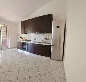 a kitchen with a refrigerator and a tile floor at Compatri House in Osteria dellʼ Osa
