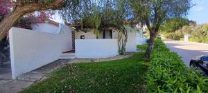 una casa blanca con árboles al lado de una calle en Cozy Beach House, en Santa Luzia