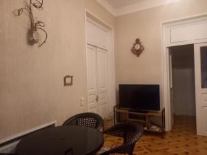 uma sala de estar com uma televisão e uma mesa e cadeiras em Old Gate em Telavi