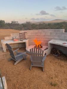 eine Feuerstelle mit 2 Stühlen und einem Tisch in der Unterkunft Peace Haven @ Windfarm Accommodation in Yzerfontein