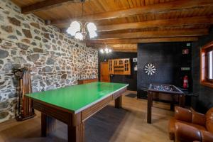 Una mesa de ping pong en una habitación con una pared de piedra. en Casinha do Quadro, en Figueiró dos Vinhos