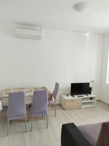 uma sala de estar com uma mesa e cadeiras e uma televisão em Apartments Nela em Zadar
