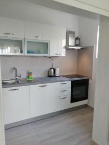 uma cozinha com armários brancos e um lavatório em Apartments Nela em Zadar