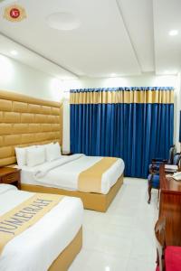two beds in a hotel room with blue curtains at Jovial Gold Naran in Nārān