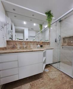 a bathroom with two sinks and a glass shower at Apart-hotel 1804 - Le Premier Suítes Jardim Paulista in Sao Paulo