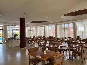 a dining room with tables and chairs and windows at Hotel Praia Sol in Quarteira