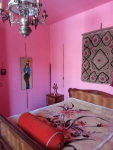 Buba في Oni: غرفة نوم بجدران وردية وسرير ببطانية حمراء