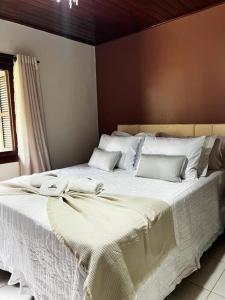 uma grande cama branca com lençóis e almofadas brancos em Otto temporada Gramado! em Canela