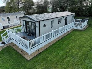 a mobile home with a porch and a deck at Hot Tub Lodge Cornwall - Meadow Lakes Holiday Park in St Austell