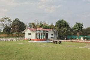 a small white house with two horses in a field at RAHA FARM in Noida