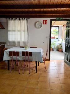 a dining room with a table and chairs and a clock at Finca Marañuela in La Perdoma