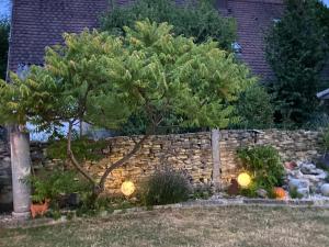una cerca de piedra con un pino en un patio en Ferienwohnung Romantica 1. und 2. OG en Schopfloch