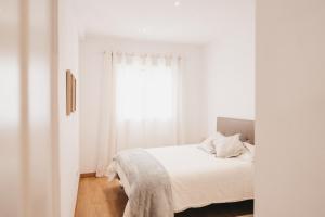 een witte slaapkamer met een bed en een raam bij Biasa Holidays in Torrox Costa