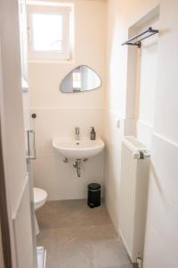 a white bathroom with a sink and a mirror at Schöne Ferienwohnung im Herzen von Itzehoe mit eigenem Eingang in Itzehoe
