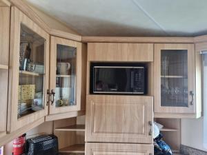 cocina con armarios de madera y microondas en Dog Friendly Caravan Heacham Norfolk Holiday, en Heacham