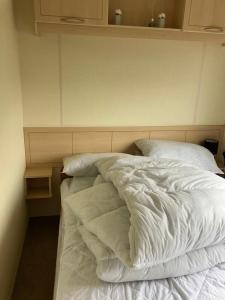 an unmade bed with white sheets in a bedroom at B&T caravans in Ingoldmells