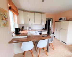 eine Küche mit einem Holztisch und weißen Stühlen in der Unterkunft BodenSEE Apartments Daisendorf nahe Meersburg in Daisendorf