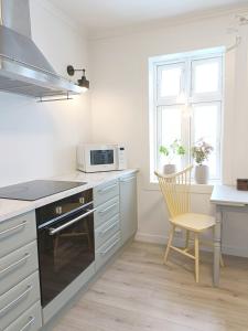 a kitchen with a stove and a microwave and a chair at Bellahuset - Charming House in Ulsteinvik in Ulsteinvik