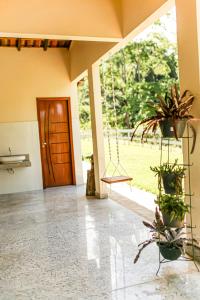 a room with a porch with a swing and potted plants at Chalés São João - a 500m da Cachoeira de Bom Jardim - com piscina in Mutum