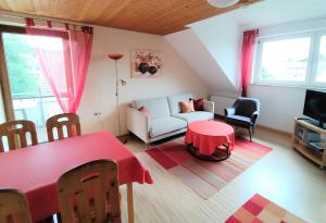 ein Wohnzimmer mit einem roten Tisch und einem Sofa in der Unterkunft BodenSEE Apartments Daisendorf nahe Meersburg in Daisendorf