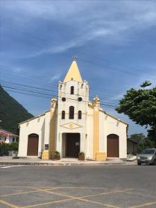 Sobrado,Armação -Sul da Ilha-Floripa في فلوريانوبوليس: كنيسة بيضاء مع وجود برج في شارع