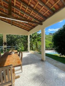 an outdoor patio with a wooden table and chairs at Chalés São João - a 500m da Cachoeira de Bom Jardim - com piscina in Mutum