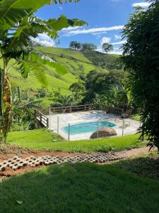 a swimming pool with a hill in the background at Chalés São João - a 500m da Cachoeira de Bom Jardim - com piscina in Mutum