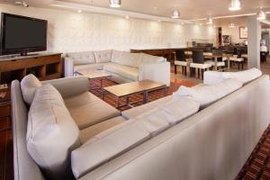 sala de estar con sofás blancos y TV de pantalla plana en Four Points by Sheraton Saltillo, en Saltillo