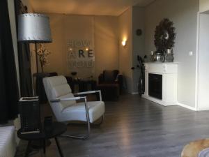 a living room with a white chair and a fireplace at Ferienwohnung Lands Huys in Dersum