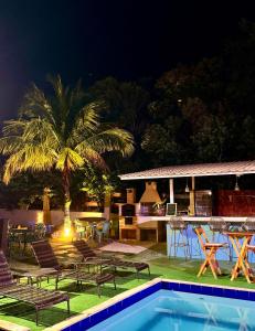 un complejo con piscina, sillas y una palmera en Estrelamar Ferradura Pousada Restaurante & Spa en Búzios