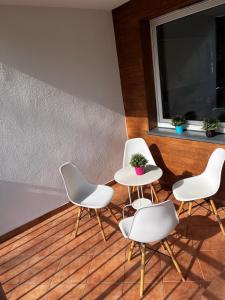 four white chairs and a table and a window at Apartament Stay with Gdynia in Gdynia