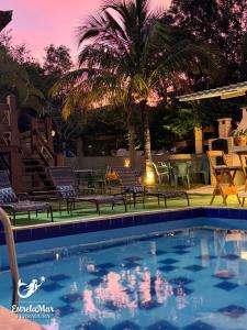a swimming pool with chairs and a palm tree at Estrelamar Ferradura Pousada Restaurante & Spa in Búzios