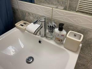 a white bathroom sink with a soap dispenser on it at Spacious Apartment near Train Station in Ljubljana