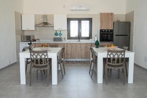 uma cozinha com mesas e cadeiras brancas e um frigorífico em Villa Marica em Partinico