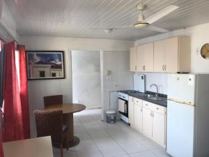 a kitchen with white cabinets and a table and a sink at Aruba Sunrise Studio Near Baby Beach, San Nicolas in San Nicolas +6 photos